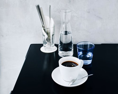 A cup of black coffee next to a glass of water on a table